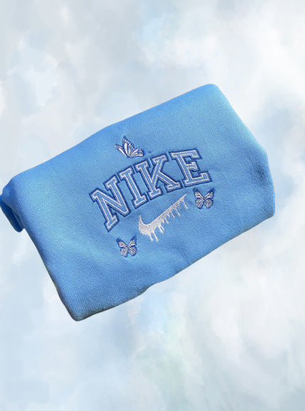 The butterfly drip nike crewneck in light blue with dark blue and white outline embroidery.