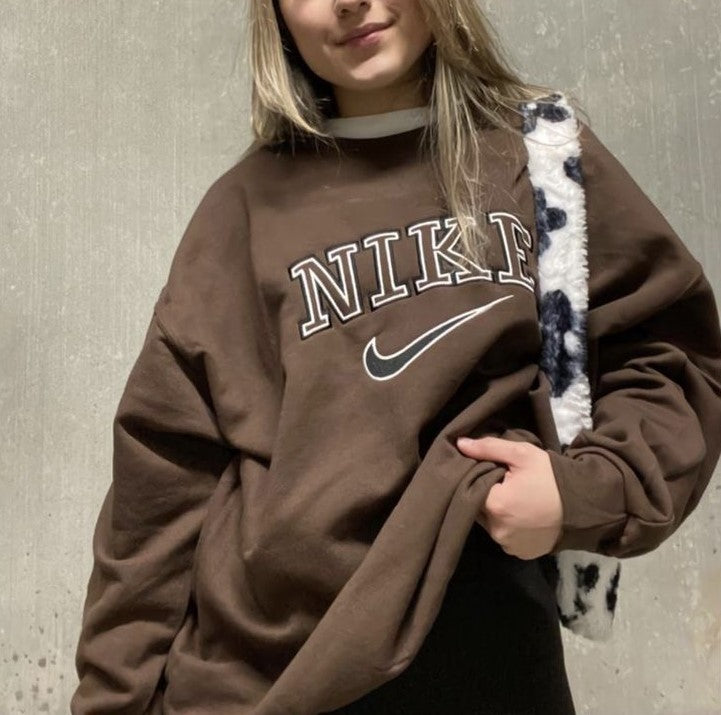 Girl posing in the dark brown nike swoosh embroidered crewneck.