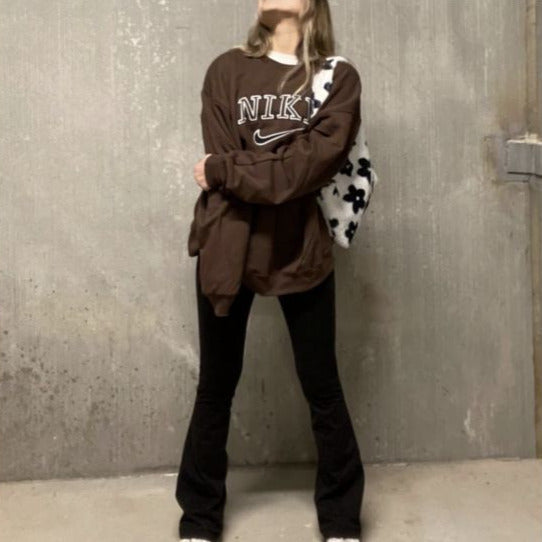 Girl posing in the dark brown nike swoosh embroidered crewneck.