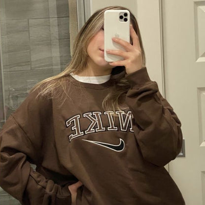 Girl posing in the dark brown nike swoosh embroidered crewneck.