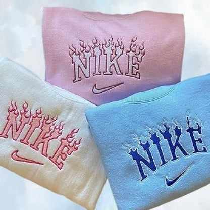 The Flames Nike embroidered crewnecks in light pink, white, and light blue.