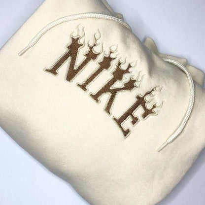 The Nike flames embroidered unisex hoodie in sand with dark chocolate embroidery.