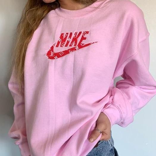 Girl wearing the LV Nike crewneck sweatshirt in light pink with red embroidery.