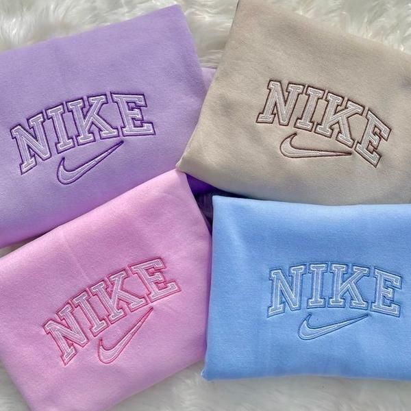 Layout of all the Nike swoosh embroidered crewnecks in purple, beige, pink, and blue.