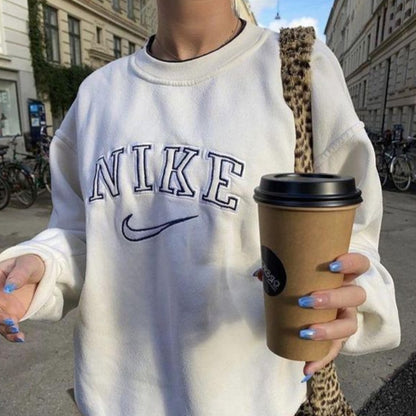 Girl posing in the trendy white nike swoosh embroidered crewneck.