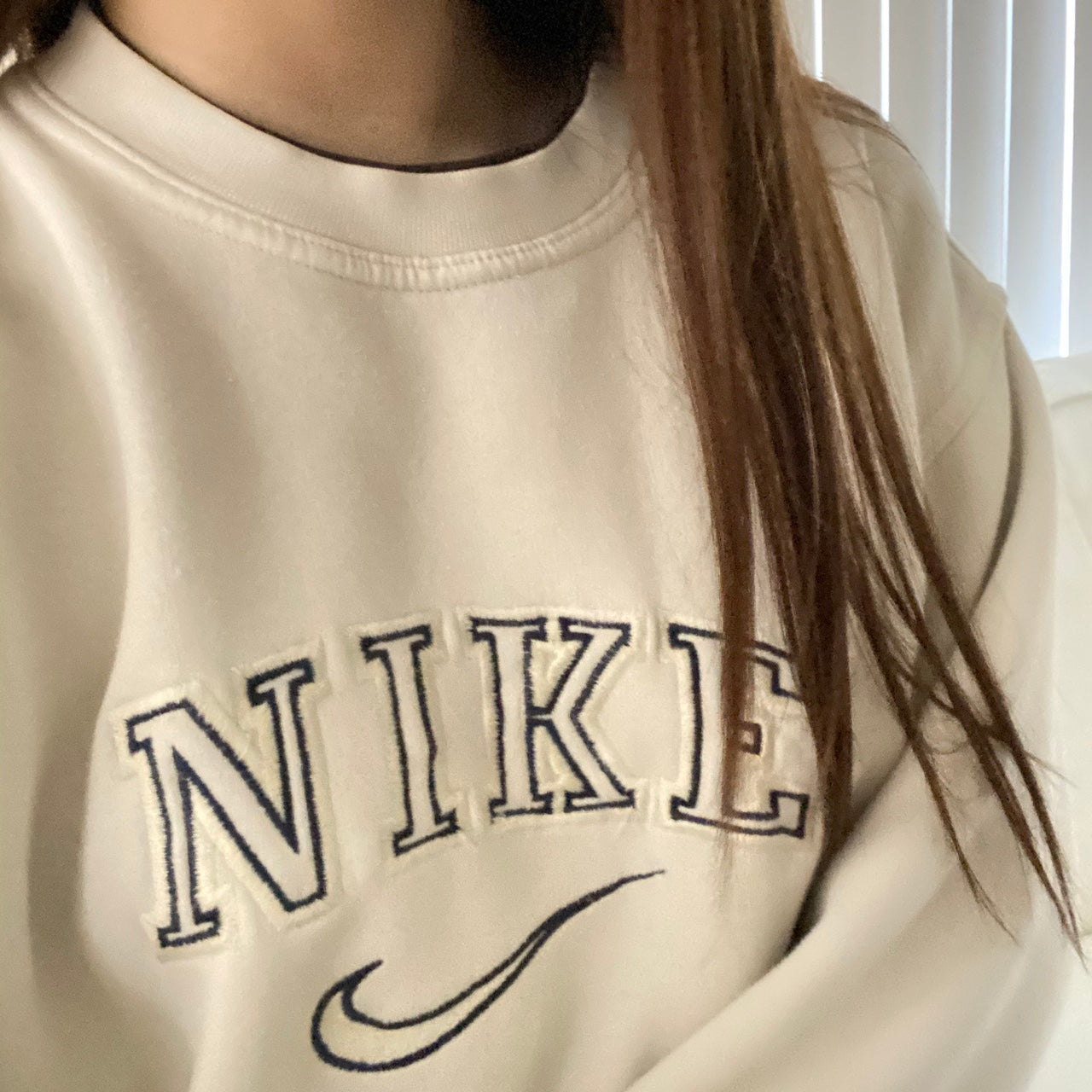 Girl posing in the beige nike swoosh embroidered crewneck.