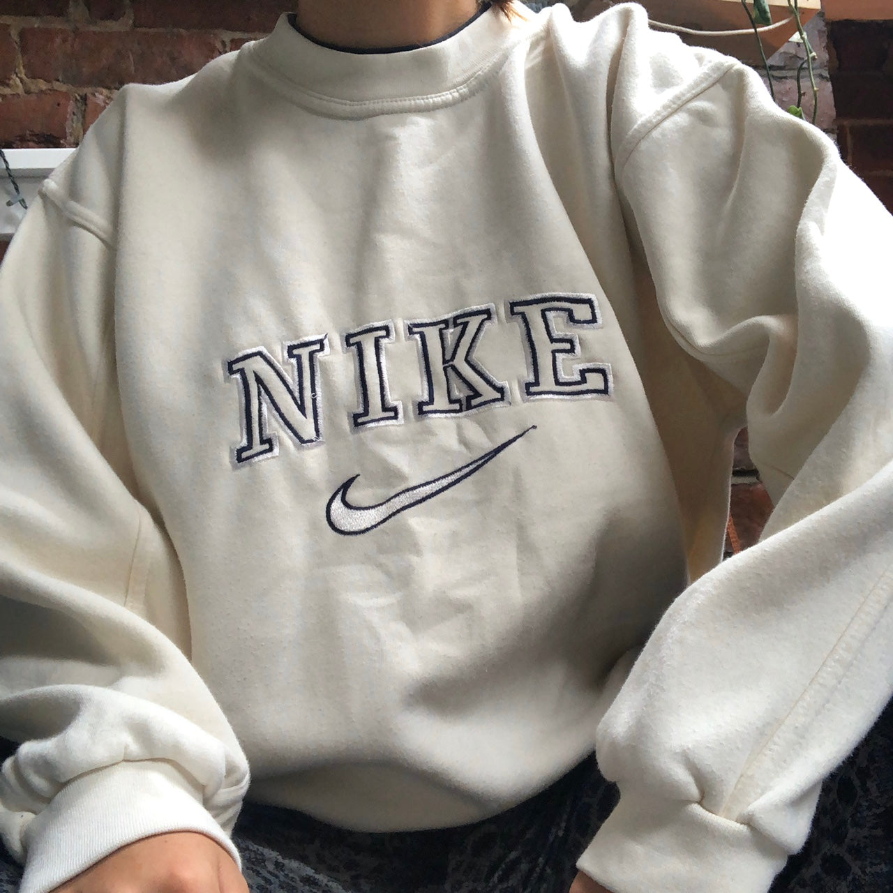 Girl posing in the beige nike swoosh embroidered crewneck.