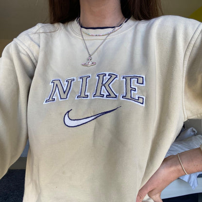 Girl posing in the beige nike swoosh embroidered crewneck.